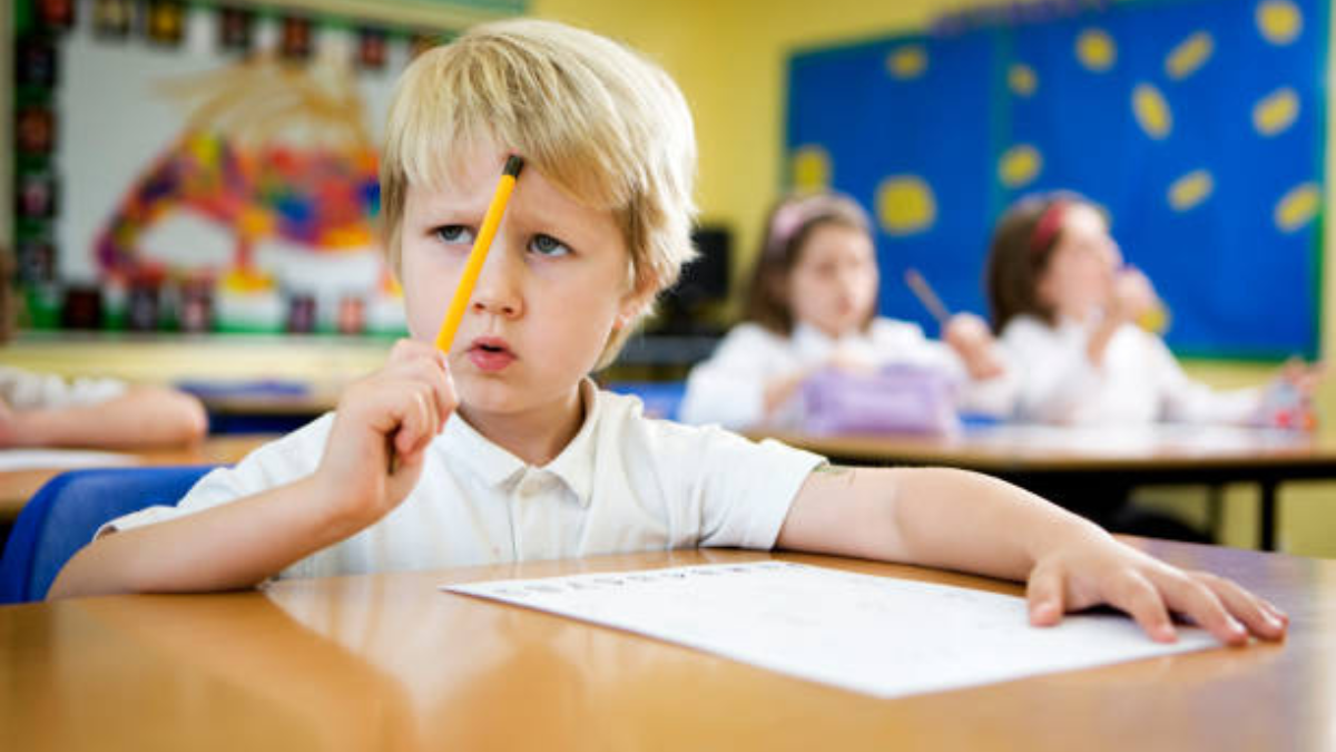 A young boy thinking at his desk, symbolizing challenges of perverted education in modern classrooms