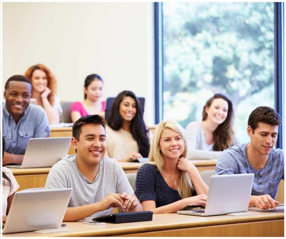 A diverse group of college students in a lecture hall. Some students are using laptops. The students are smiling. Financial Aid Guides for Students