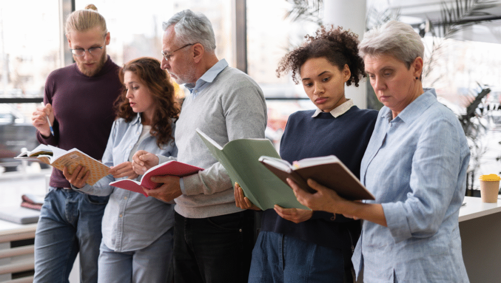 Perennial Education: Shaping Minds Beyond Time A diverse group of adult learners reading books together in a bright classroom, representing lifelong learning and the concept of perennial education