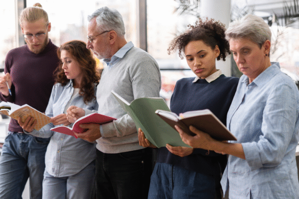 A diverse group of adult learners reading books together in a bright classroom, representing lifelong learning and the concept of perennial education
