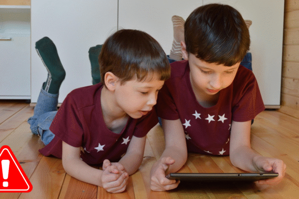 Two young boys on a floor viewing a tablet, symbolizing the potential negative impact of short content on children's minds.