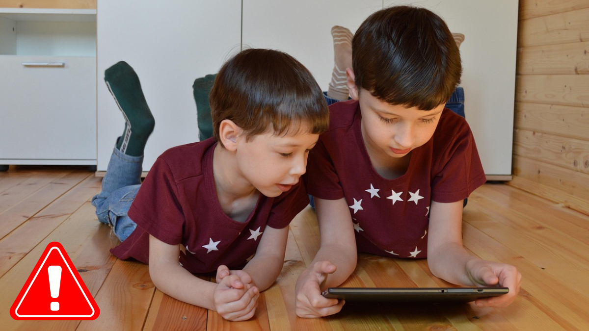 Two young boys on a floor viewing a tablet, symbolizing the potential negative impact of short content on children's minds.
